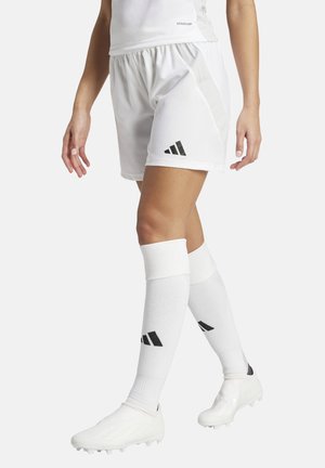 Witte sportieve shorts met een gestructureerde afwerking, voorzien van een zwart logo met drie strepen. Gecombineerd met witte kniehoge sokken en voetbalschoenen.