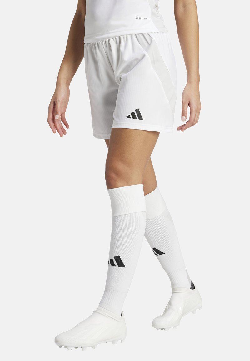 Witte sportieve shorts met een gestructureerde afwerking, voorzien van een zwart logo met drie strepen. Gecombineerd met witte kniehoge sokken en voetbalschoenen.
