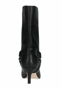 Botte en cuir noir hauteur genou avec un bout pointu, un talon haut et un détail de sangle à la cheville avec fermeture à boucle. Texture lisse avec peu de coutures.