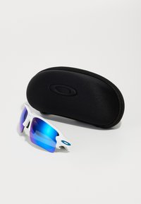 Białe sportowe okulary przeciwsłoneczne z niebieskimi lustrzanymi soczewkami, cechujące się aerodynamicznym kształtem i charakterystycznym logo, w zestawie z czarnym futerałem ochronnym.