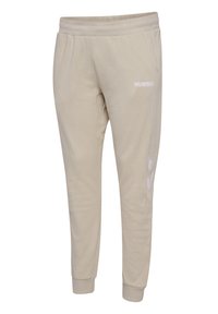 Beige Jogginghosen aus weichem Stoff, mit einem weißen "HUMMEL"-Logo und zwei weißen Chevron-Mustern an den Seiten, mit schmal zulaufenden Bündchen.