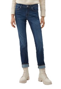 Mörkblå denimjeans med smal passform, med framfickor och uppvikta mudd. Matchas med beige snörstövletter.