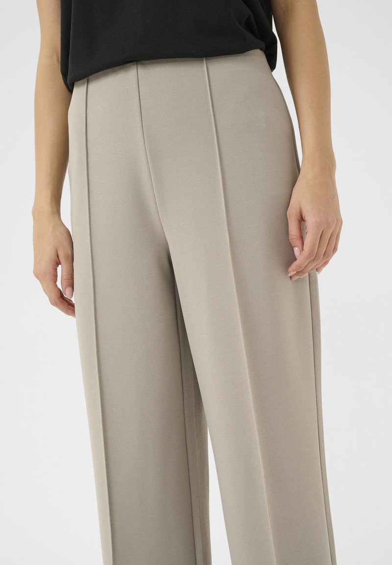 Beige wijde broek van zachte stof met een gladde textuur, voorzien van frontplooien en een hoge taille.