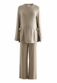 Beiges Loungewear-Set aus zwei Teilen mit einem langärmeligen Oberteil, das seitliche Taschen hat, und einer weit geschnittenen Hose aus einem weichen, strukturierten Stoff.