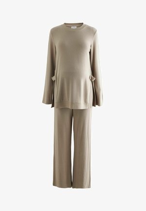 Ensemble de loungewear beige en deux pièces avec un haut à manches longues comportant des poches latérales et un pantalon à jambes larges en tissu doux et texturé.