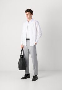Weißes Hemd mit Knöpfen, graue Anzughose und schwarze Schuhe. Hält eine schwarze Ledertasche. Schlichtes, maßgeschneidertes Design, glattes Material.