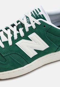 Green suede sneaker with white leather accents, featuring a large white "N" logo, white laces, and a textured rubber sole.