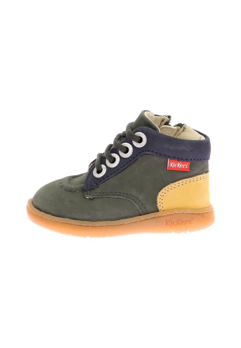 Botín infantil en ante verde oscuro con acentos en azul marino, panel lateral beige, ojales plateados y suela de goma marrón. Cierre de cordones ajustable.