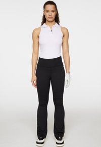 Vit ärmlös polo med dragkedja fram, matchat med svarta utsvängda byxor. En vit handske på höger hand, svart och vita skor.