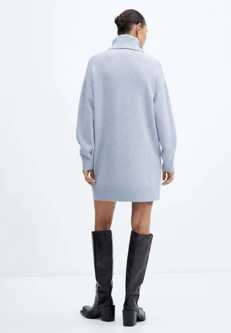 Robe-pull bleu clair oversize avec un col montant et un ourlet côtelé, associée à des bottes noires montantes à talon bloc.