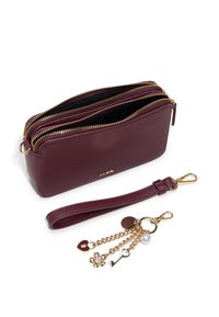 Borsa in pelle bordeaux con due scomparti con zip, accessori in metallo dorato e una tracolla rimovibile. Presenta dettagli con charms.