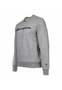 Sivý sveter s kruhovým výstrihom vyrobený z bavlneného zmesi, s čiernym logom "Champion" napísaným cez prednú stranu a malým detailom loga na rukáve.