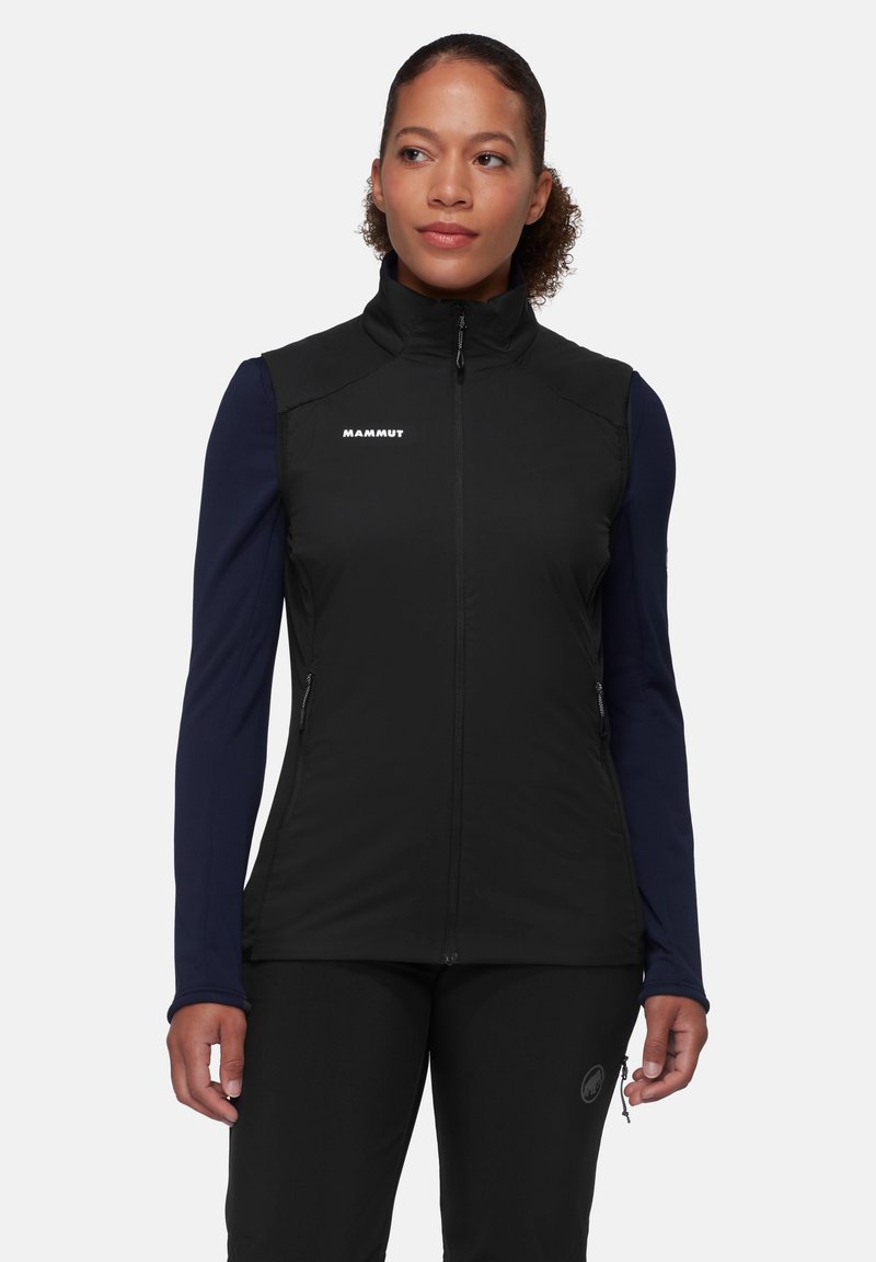 Black vest with a high collar, zippered front, and side pockets, featuring a smooth texture and white logo on the chest. Worn over long sleeves.