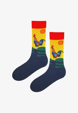 Para skarpetek z czerwonymi mankietami, granatowymi stopami i żółtą górą z kolorowym kogutem stojącym na zielonych wzgórzach z pomarańczowym słońcem.