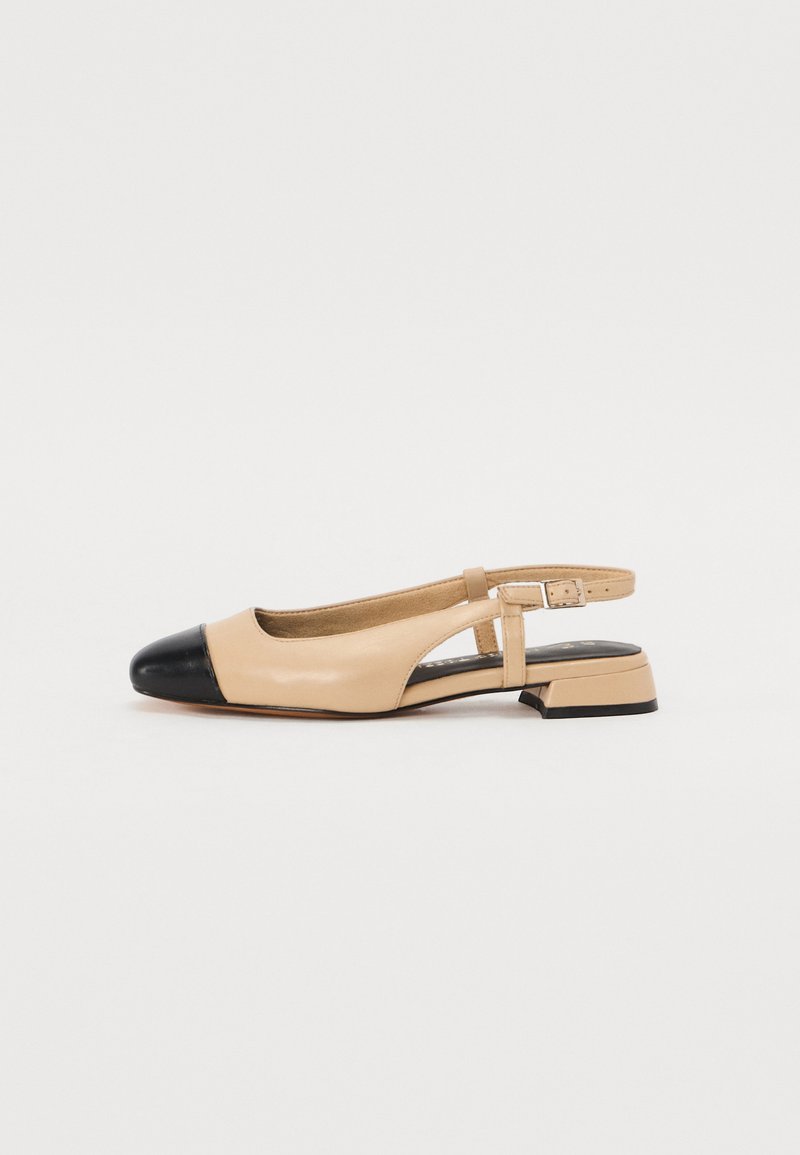 Beżowe skórzane buty na obcasie typu slingback z czarnym noskiem, niskim blokowym obcasem, otwartymi bocznymi wycięciami oraz regulowanym paskiem na kostce.