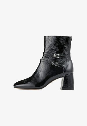 Bottine en cuir verni noir avec bout pointu, deux brides décoratives à boucles argentées et talon bloc.