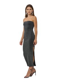 Abito midi aderente senza spalline in nero con finitura metallizzata, caratterizzato da fessure laterali alte fino alla coscia e una texture liscia. Abbinato a tacchi a laccio.