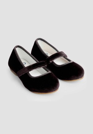 Mustat samettiset Mary Jane -kengät, joissa on pyöreä kärki, litteä pohja ja koristeellinen remmi karmiin yli. Pehmeä rakenne ja minimalistinen muotoilu.