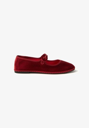 Bailarinas de terciopelo rojo con punta redonda, un lazo decorativo en el empeine y un borde de costura contrastante a lo largo de la suela.