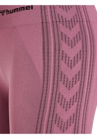 Leggings compressivi di colore rosa chiaro con motivi testurizzati e accenti neri, dotati di una vita a coste e di un design a maglia dettagliato.