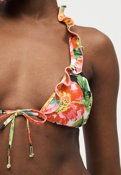 Κοντινό πλάνο ενός ατόμου που φοράει φλοράλ μπικίνι τοπ με βολάν στα τιράντες και δεμένες κορδονάκια μπροστά, με έντονα πορτοκαλί, ροζ και πράσινα χρώματα.