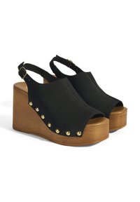 Schwarze Wildleder-Wedge-Sandalen mit offener Zehe, Slingback-Riemen und goldenen Nieten an der Außenseite. Die Holzplattform sorgt für zusätzliche Höhe.