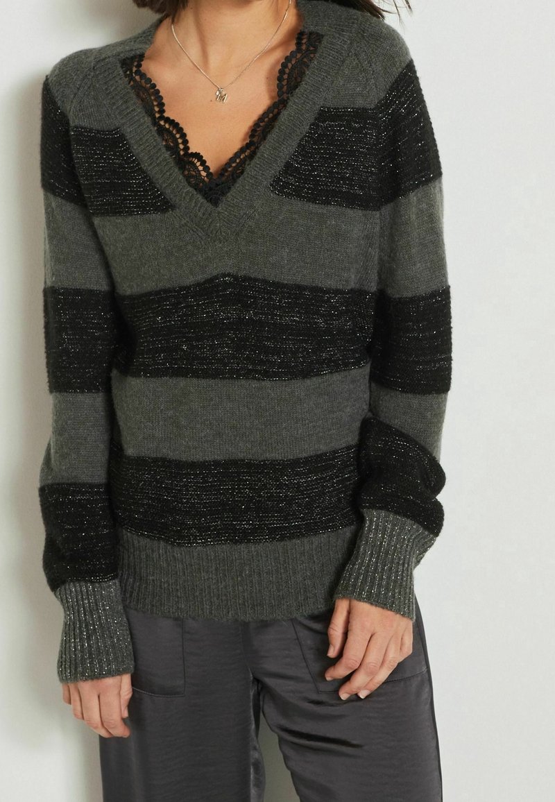 Maglione grigio a righe con strisce nere texture, scollo a V e bordo in pizzo. Polsini e orlo a coste con vestibilità rilassata.