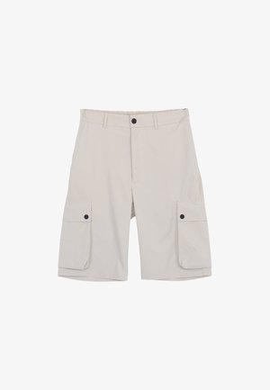 Short cargo beige longueur genou avec poches latérales boutonnées, passants de ceinture et fermeture par bouton noir à la taille.