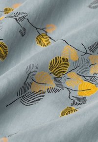 Lyseblåt stof med et løvmønster i gult og sort. Designet indeholder indviklede linjedetaljer og varierede løvformer.