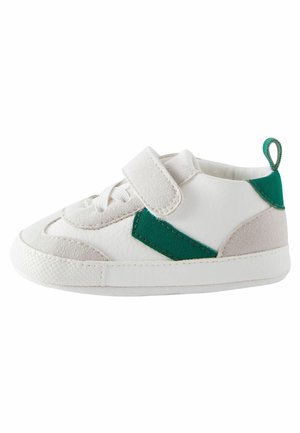 Petite basket blanche avec des accents verts, une bride en Velcro et des lacets, conçue pour les tout-petits avec une semelle texturée pour l’adhérence.