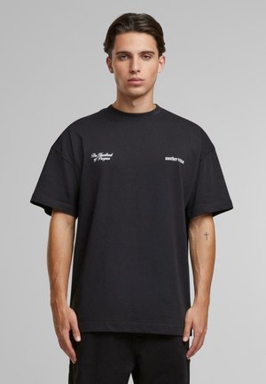 Black cotton t-shirt featuring a relaxed fit, short sleeves, and white text graphics on the chest. Smooth texture and minimalistic design.