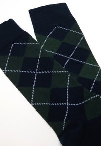 Calzini argyle blu scuro e verdi con un motivo a diamante, caratterizzati da accenti di cucitura bianca. Realizzati in un morbido tessuto lavorato a maglia.