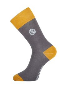 Chaussette mi-mollet avec un corps gris, une bordure, un orteil et un talon jaune moutarde, présentant un petit logo circulaire blanc et le texte "SERGE BLANCO" sur le côté.