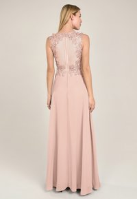 Abito lungo rosa con schiena trasparente e ricami in pizzo floreale. Tessuto morbido, lunghezza fino al pavimento, senza maniche, chiusura con zip sul retro.
