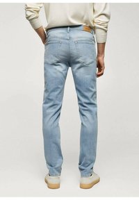 Vaaleansiniset farkut, joissa on slim-fit-istuvuus, takataskut ja nahkainen merkki vyötäröllä. Sileä pinta ja vähäiset ompelukohdat.