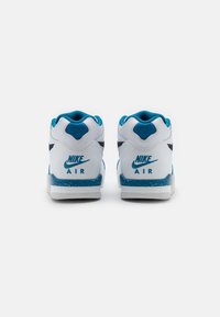 Bílé tenisky s modrými akcenty, vyrobené z texturovaného materiálu, s polstrovaným límcem a logem na patě. Plochá podrážka se skvrnitým detailem.