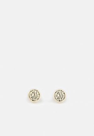 Round gold-tone stud earrings with "DKNY" initials and "Donna Karan New York 1989" text around the edges.