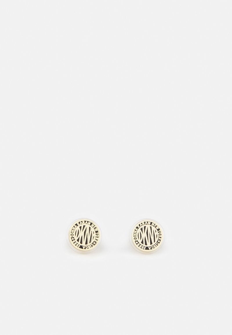 Boucles d'oreilles à clous rondes de couleur or avec les initiales "DKNY" et le texte "Donna Karan New York 1989" autour des bords.