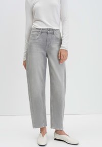 Light gray denim jeans with a straight-leg design, featuring a mid-rise waist, front pockets, and subtle fading detail. Paired with white shoes.