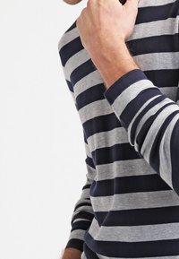 Långärmad tröja i marinblå och grå randig design. Har en rund halsringning, mjukt bomullstyg och en smal passform som framhäver djärva horisontella ränder.