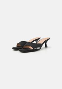 Fekete sarkú mules sima anyagú felsőrésszel, nyitott orral és ívelt sarokkal. Az oldalán a "LOVE MOSCHINO" fehér logó látható.