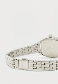 Silver stainless steel watch with a rectangular case, smooth surface, and linked strap featuring a secure clasp and minimalist design.