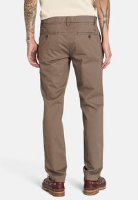 Ruske puuvillased püksid sirge fitsiga, kus on kaks tagataskut ja sobivad ruskeid kingi. Kangas on sile ja minimaalse tekstuuriga.