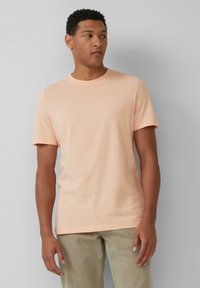 Korte mouwen, ronde hals t-shirt van zacht perzikkleurig materiaal. Heeft een subtiele logo op de borst en een standaard pasvorm. Licht textuur, casual ontwerp.