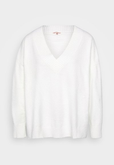White, oversized sweater with a V-neck, textured fabric, and ribbed cuffs and hem. Soft material with a fuzzy appearance.