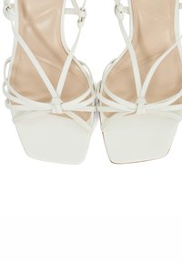 White high-heel sandals with a square toe design, featuring multiple thin straps and a smooth finish on the insole and outsole.
