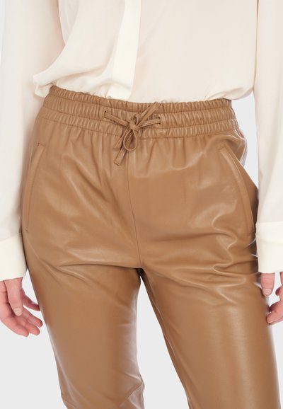 Pantalon en simili cuir marron avec une taille élastique munie d'un cordon de serrage, des poches latérales et une texture lisse et brillante.