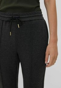 Mörkgrå sweatpants med dragsko i midjan, med guldspetsade ändar, tillverkade av mjukt, texturerat tyg.