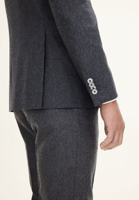 Blazer grigio scuro realizzato in tessuto testurizzato, caratterizzato da una vestibilità slim, uno spacco singolo e quattro bottoni decorativi sui polsini. Pantaloni grigi slim-fit.