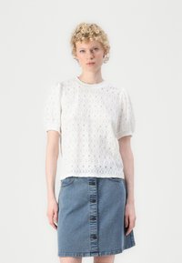 Witte oogjes kant blouse met poffende mouwen, ronde hals, gecombineerd met een denimrok met een sluiting aan de voorkant en twee zakken.